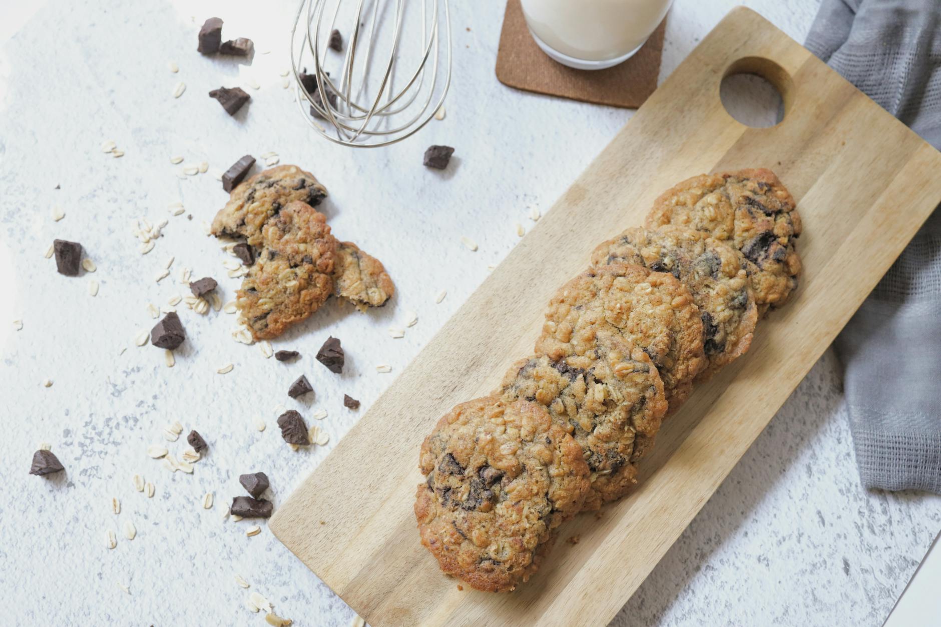 Ciastka z kawałkami czekolady na desce obok szklanki mleka