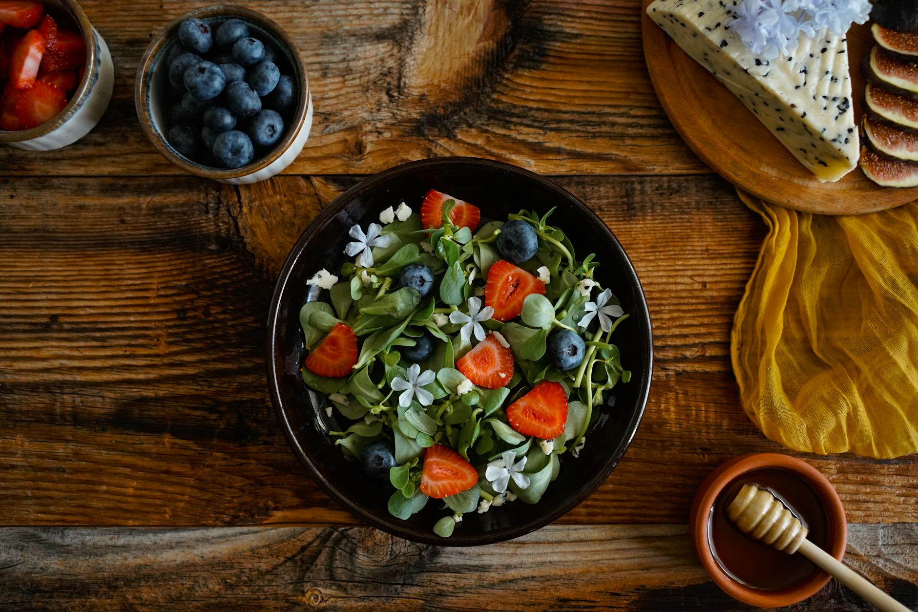 Letnia sałatka z truskawkami, borówkami i serem na drewnianym stole