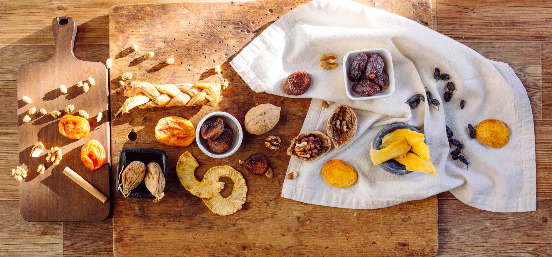 Suszone owoce na drewnianym stole obok ściereczki i deski do krojenia