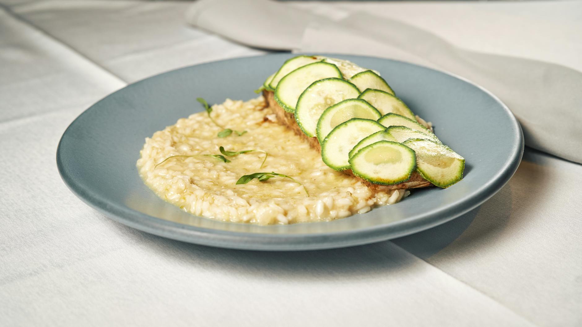 Risotto na talerzu udekorowane świeżymi plasterkami cukinii