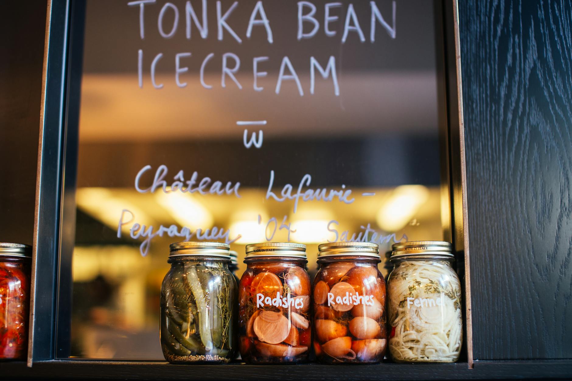 Szklane słoiki z kiszonymi warzywami na półce w jasnym wnętrzu