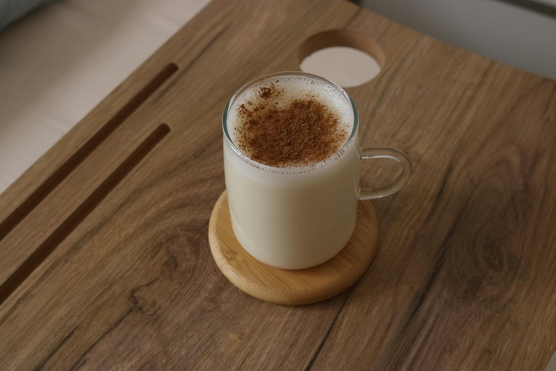 Kremowy napar chai z mlekiem roślinnym i cynamonem w szklance na podstawce