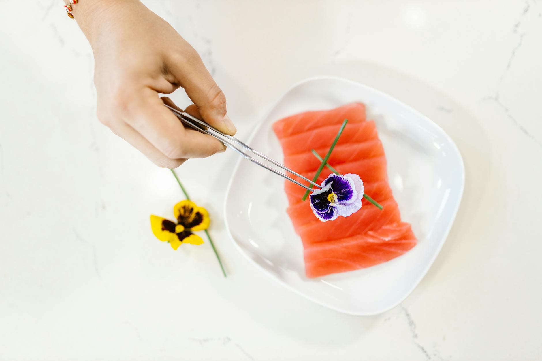 Plasterki tuńczyka sashimi na talerzu z jadalnym kwiatem bratka