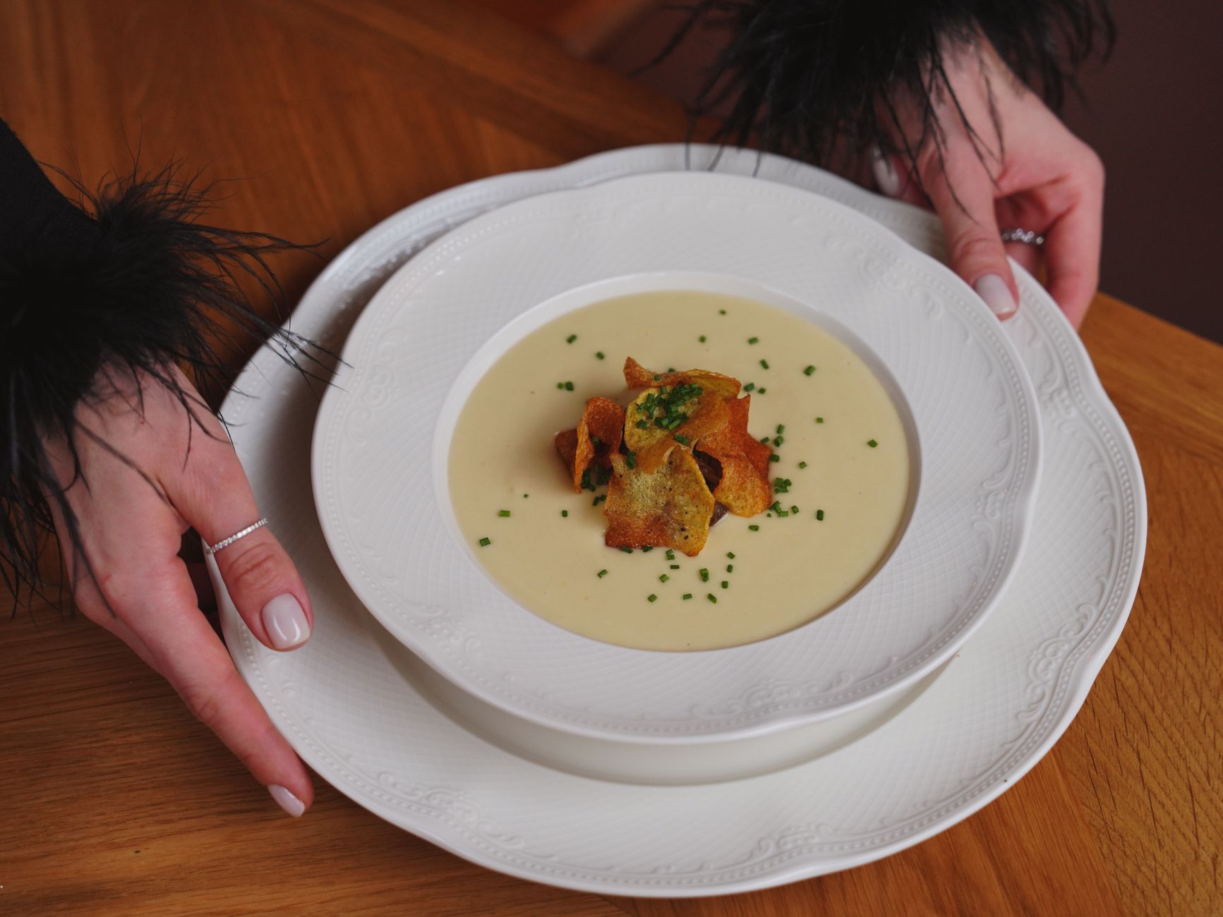 Kremowa zupa z chrupiącą posypką podana w białym talerzu restauracyjnym