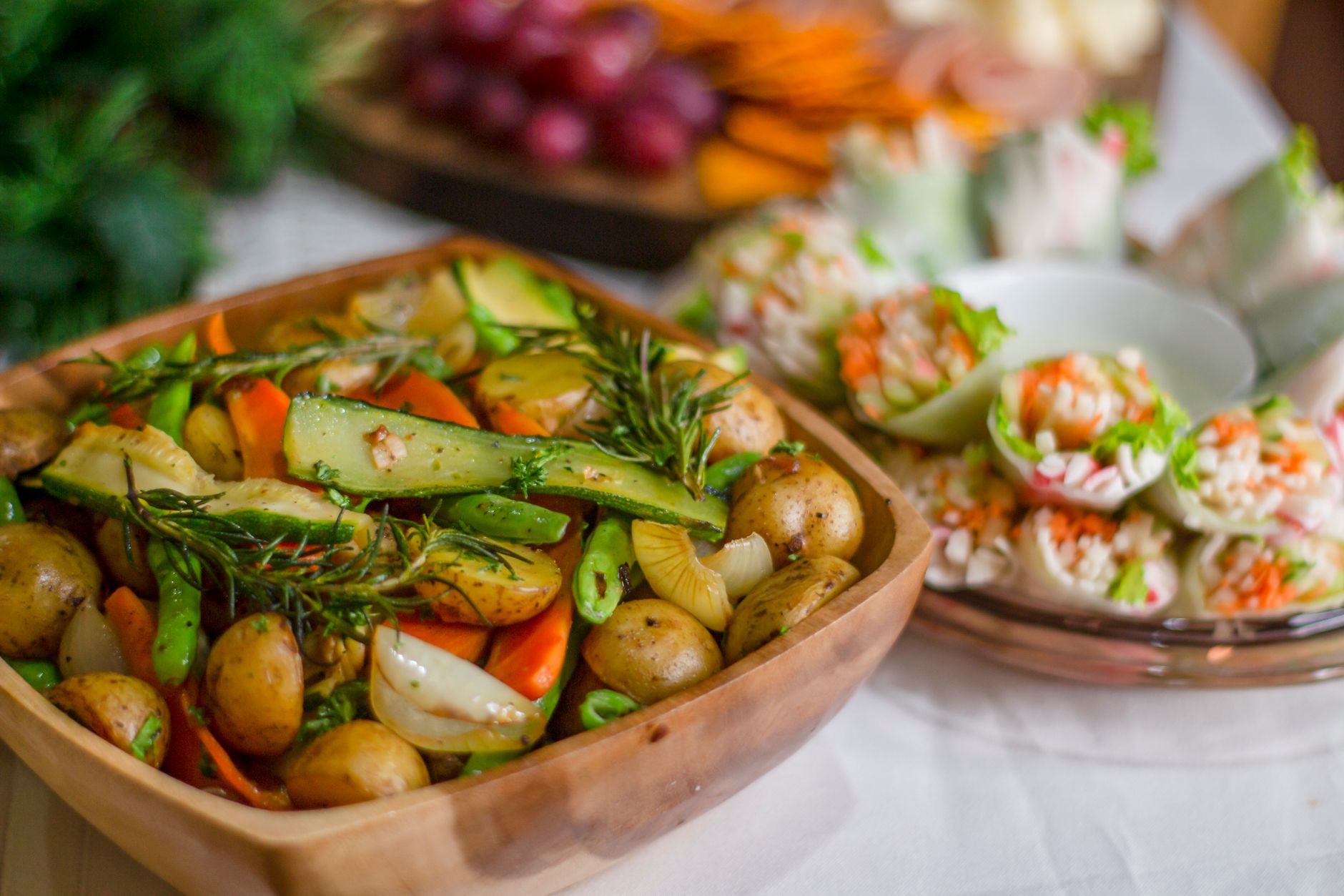 Kolorowe pieczone warzywa z ziołami i spring rolls na drewnianej desce