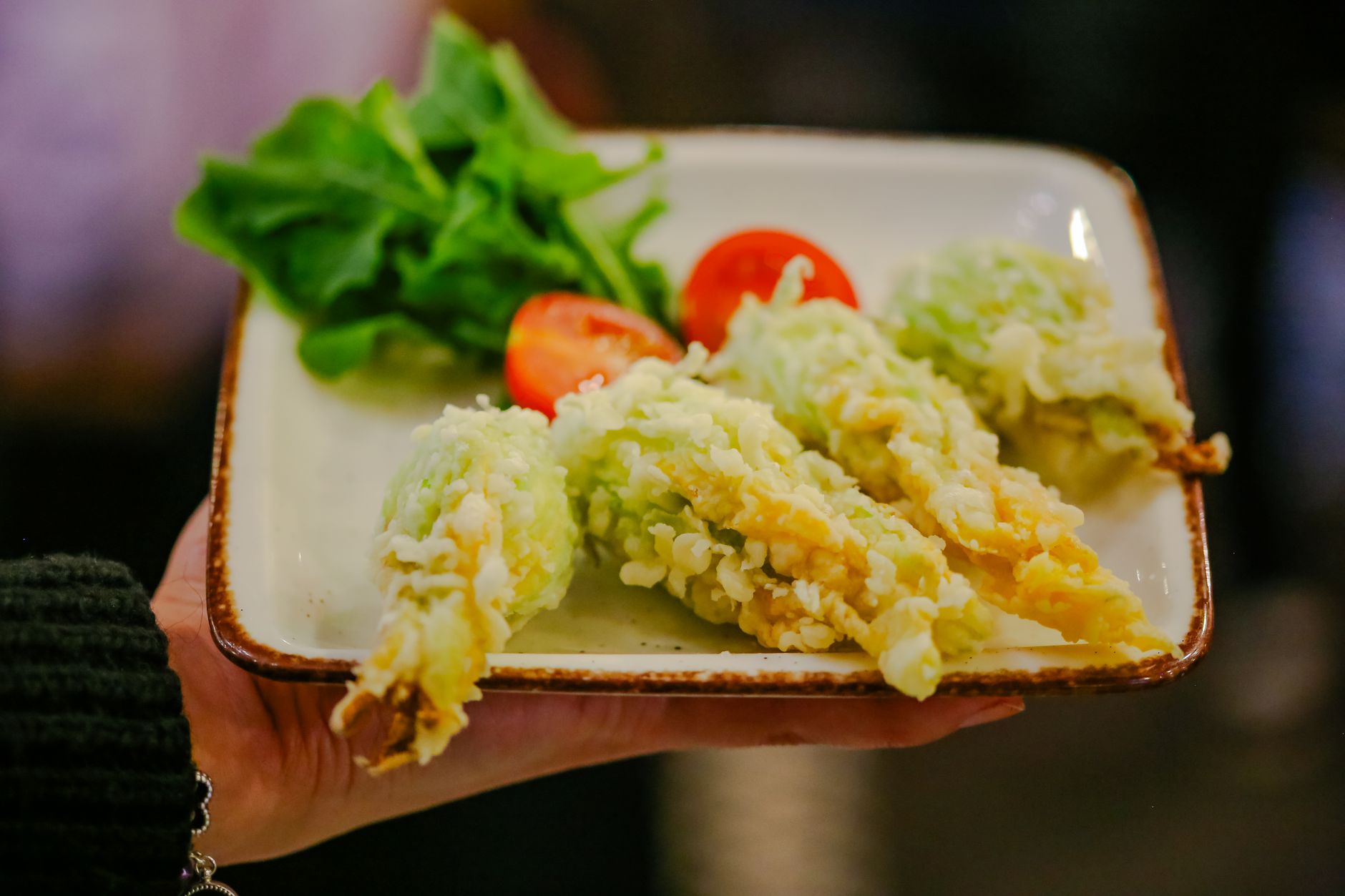 Tempura z kwiatów cukinii z pomidorami i sałatą na kwadratowym talerzu